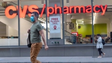A person wearing a mask walking by a CVS pharmacy A person wearing a mask walking by a CVS pharmacy