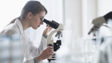 Technician looking into a microscope Technician looking into a microscope