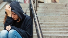Person sitting on steps with their head in their hands Person sitting on steps with their head in their hands