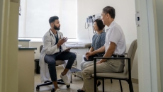 Doctor sitting in an exam room with two patients Doctor sitting in an exam room with two patients
