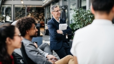 Several people sitting in a garden area near a building looking at something out of the picture Several people sitting in a garden area near a building looking at something out of the picture