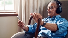 Person sitting, holding a cane, looking at their phone Person sitting, holding a cane, looking at their phone