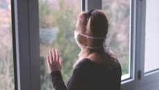 Person Wearing mask looking out window Person wearing mask looking out window