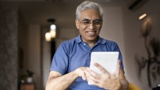 An elderly using a digital tablet at home An elderly using a digital tablet at home