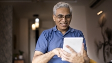 Person at home smiling and looking at a tablet Person at home smiling and looking at a tablet