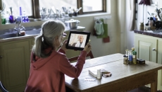 Person sitting at a table looking at a tablet Person sitting at a table looking at a tablet
