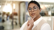 Person sitting in a clinical setting while holding a pen to their chin Person sitting in a clinical setting while holding a pen to their chin
