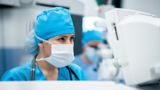 Surgeon standing in front of a computer dressed in surgical gear Surgeon standing in front of a computer dressed in surgical gear