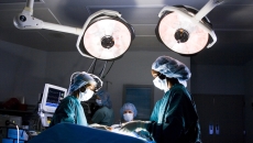 Surgeons standing around an operating table performing surgery Surgeons standing around an operating table performing surgery