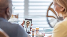 A couple talking to a provider through a video chat on a smartphone. A couple talking to a provider through a video chat on a smartphone.