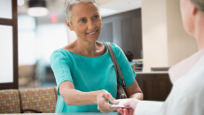 Person handing a piece of paper to a healthcare professional Person handing a piece of paper to a healthcare professional