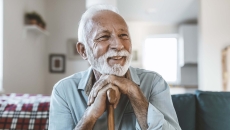 Person sitting on their ouch while holding their cane Person sitting on their ouch while holding their cane