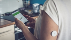 Image of person with glucose patch looking at a smartphone Image of person with glucose patch looking at a smartphone