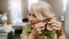 Person adjusting their hearing aid Person adjusting their hearing aid