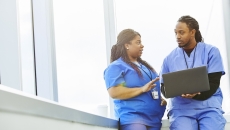Healthcare professionals conferring while using a laptop computer Healthcare professionals conferring while using a laptop computer