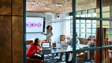 A woman presents in front of a group of colleagues A woman presents in front of a group of colleagues