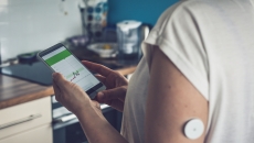 A close up of a person wearing a CGM while tracking glucose levels on their phone A close up of a person wearing a CGM while tracking glucose levels on their phone