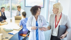 A businessperson talks with a doctor in a hospital board room. A businessperson talks with a doctor in a hospital board room.
