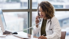 A doctor talking on a phone while taking notes. A doctor talking on a phone while taking notes.
