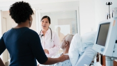 A doctor talking to patient and his family in a hospital room. A doctor talking to patient and his family in a hospital room.