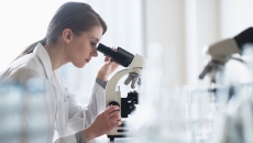 A lab technician analyzing a sample through a microscope A lab technician analyzing a sample through a microscope