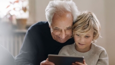 An older man and a child using a tablet together