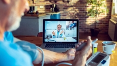 A patient talking to a doctor through a video chat on his computer while using a connected blood pressure device. A patient talking to a doctor through a video chat on his computer while using a connected blood pressure device.