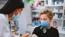 An older person receiving a vaccine in a pharmacy. An older person receiving a vaccine in a pharmacy.