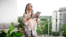 An older woman using a tablet at her desk An older woman using a tablet at her desk