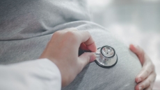 A health professional placing a stethoscope on a pregnant belly A health professional placing a stethoscope on a pregnant belly