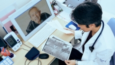 A provider holding imaging results talking to a patient via telehealth A provider holding imaging results talking to a patient via telehealth