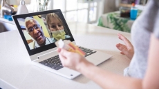 A close up of a woman holding a prescription while talking to two providers on her laptop A close up of a woman holding a prescription while talking to two providers on her laptop
