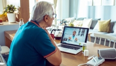 A man talking to a doctor via a laptop with connected devices like a blood pressure cuff and a thermometer A man talking to a doctor via a laptop with connected devices like a blood pressure cuff and a thermometer