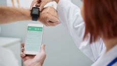 Doctor showing senior patient how to synchronize health app in smartphone and smartwatch