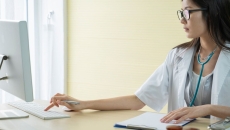 A doctor researching about a patient's condition using a desktop computer A doctor researching about a patient's condition using a desktop computer
