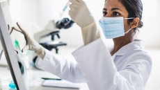 Person wearing mask holding test tube Person wearing mask holding test tube