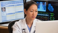 A doctor reading a patient's file on a laptop A doctor reading a patient's file on a laptop