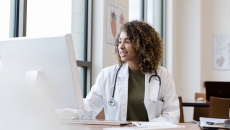 A doctor reviewing a patient record on a desktop computer A doctor reviewing a patient record on a desktop computer