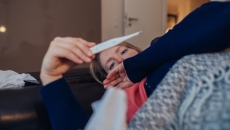 A sick woman looking at a thermometer