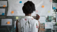 Person looks at plans posted on office wall Person looks at plans posted on office wall