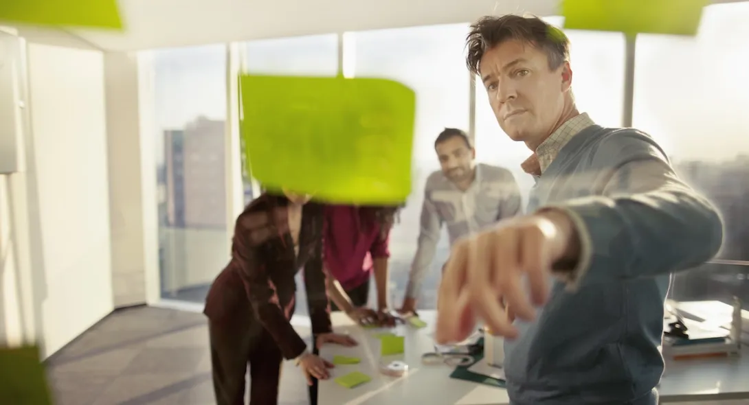 People standing in a room looking at a wall of post-its People standing in a room looking at a wall of post-its
