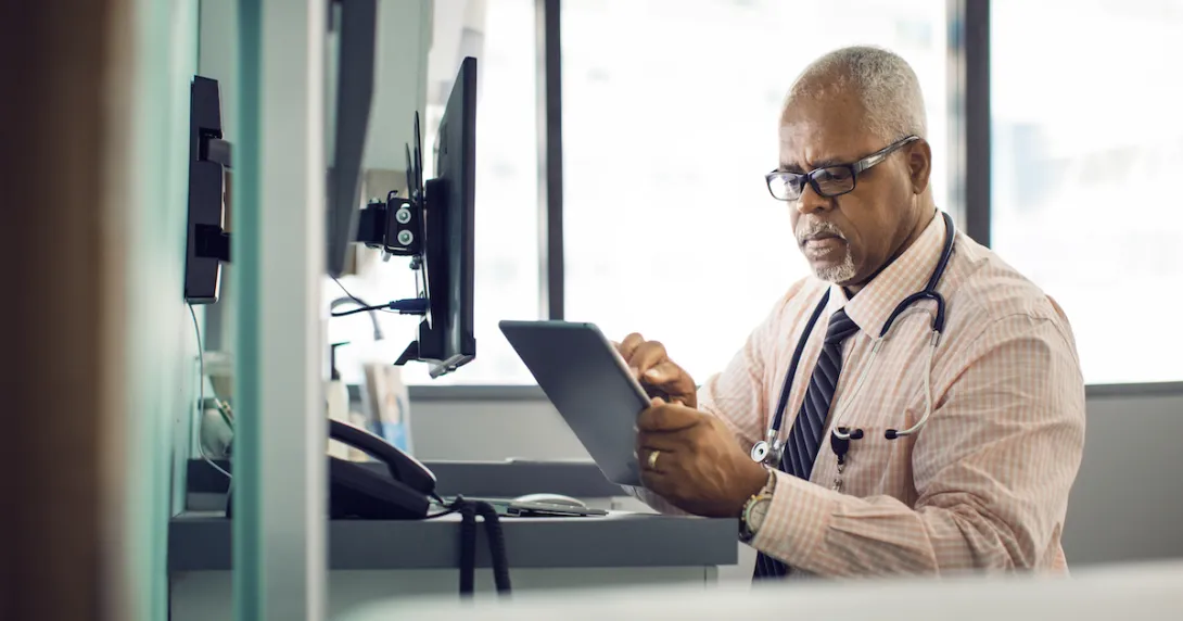 
  Healthcare provider sitting at a desk while looking at a tablet
