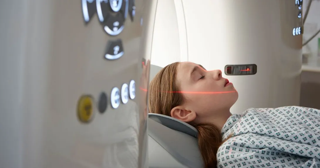 Person lying just outside an MRI machine with a red scanning light on their face Person lying just outside an MRI machine with a red scanning light on their face