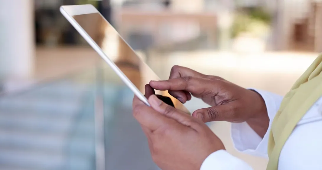 
  Person's hands holding a tablet while wearing a yellow scarf 

