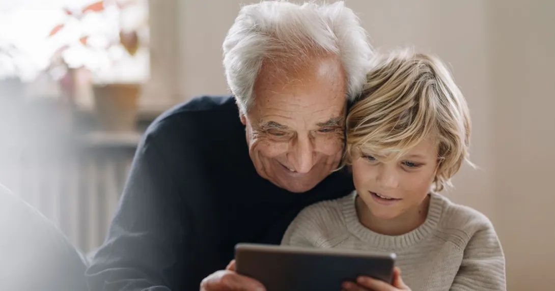 An older man and a child using a tablet together